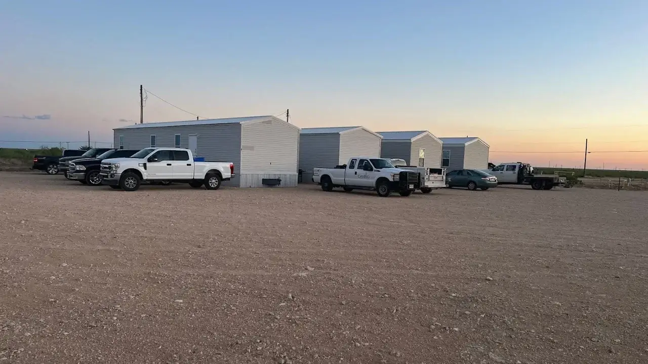 Housing units at Goldsmith RV Park & Housing with work trucks parked out front at sunset